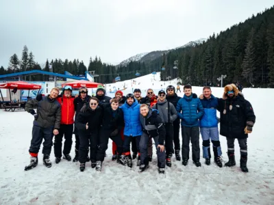 A group of men take a photo in front of a ski lift and snowy forest in Slovakia