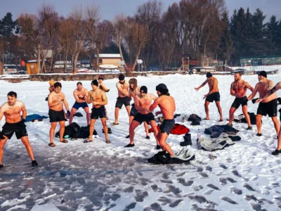 A group of shirtless men do stretches on the ice