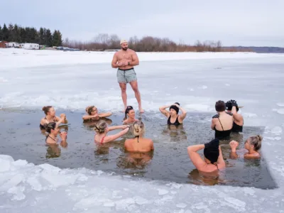 12 women in an ice bath and a man standing in front of them